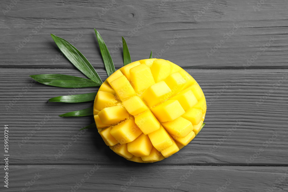 Cut ripe mango and palm leaf on wooden background, space for text Cut ripe mango and palm leaf on wooden background, space for text