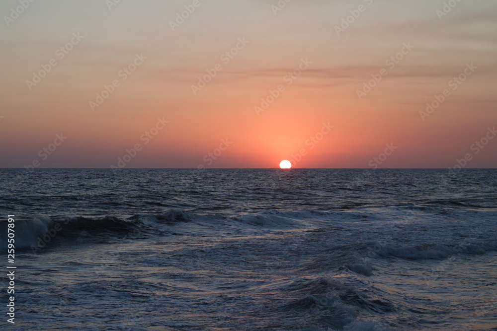 Orange sun halfway disappeared into the ocean. Orange sun halfway disappeared into the ocean.