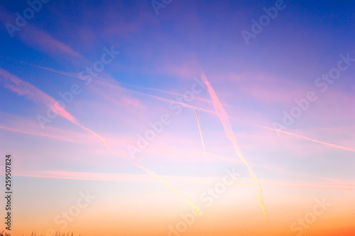 Фотография Spectacular sunset sky with vapour trails and high clouds.