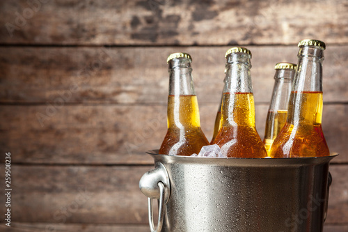 Obraz na plátne Cold bottles of beer in the bucket on the wooden background