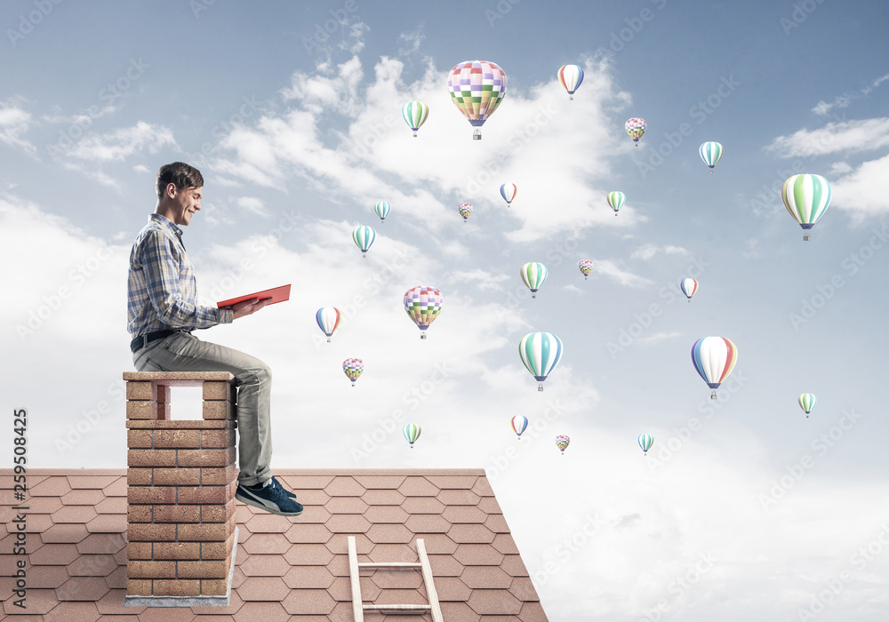 Handsome student guy reading book and aerostats flying in air Handsome student guy reading book and aerostats flying in air