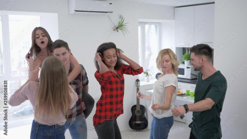 friends playing with confetti in the kitchen in slow motion, multiracial youth are dancing and having fun at a home party friends playing with confetti in the kitchen in slow motion, multiracial youth are dancing and having fun at a home party