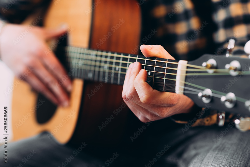 Fototapeta premium Guitar player. Selective focus of male fingers touching strings while playing the guitar