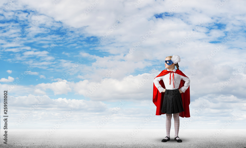 Girl power concept with cute kid guardian against cloudscape background . Mixed media