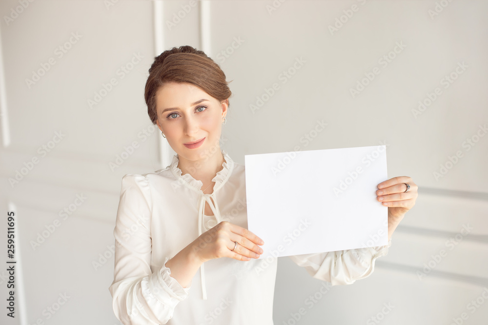 young smiling woman holding a blank sheet of paper for advertising.Girl showing banner with copy space young smiling woman holding a blank sheet of paper for advertising.Girl showing banner with copy space