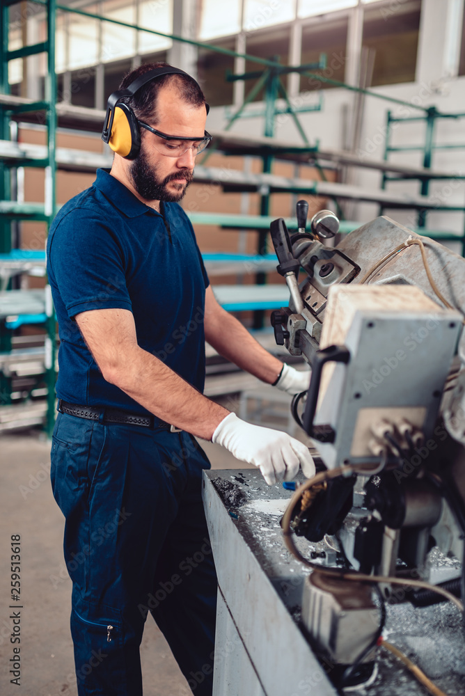 Factory worker operating band saw cutting machine Factory worker operating band saw cutting machine