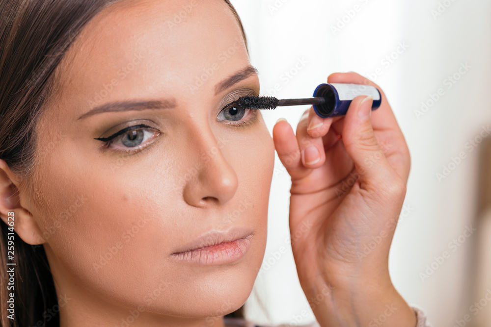Make up artist applying mascara on client's eyelashes
