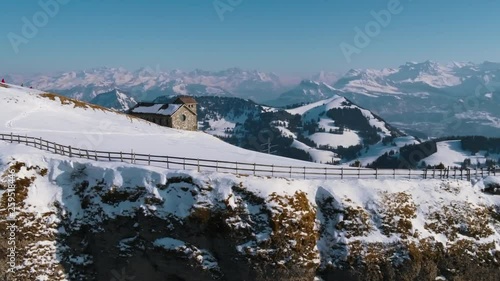 A drone movie along a mountain cliff with a stuning scenic view.
A fantastic movie on a winterday in the mountains.
There is also a little house visible on the top of the mountain. photo