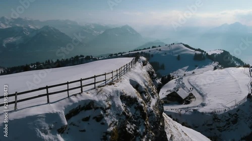 A drone movie along a mountain cliff with a stuning scenic view.
A fence is visible on the edge of the cliff. A fantastic movie on a winterday in the mountains. photo