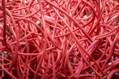 A bunch of highly entangled red electrical wires. Confusion, chaos, disorder. Waste or wire scraps are very much intertwined. Flexible stranded wires.