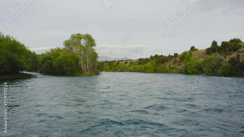 Aerial reveal of the red Luggate bridge located in Wanaka New Zealand as camera tracks backwards low to the river and a car crosses photo