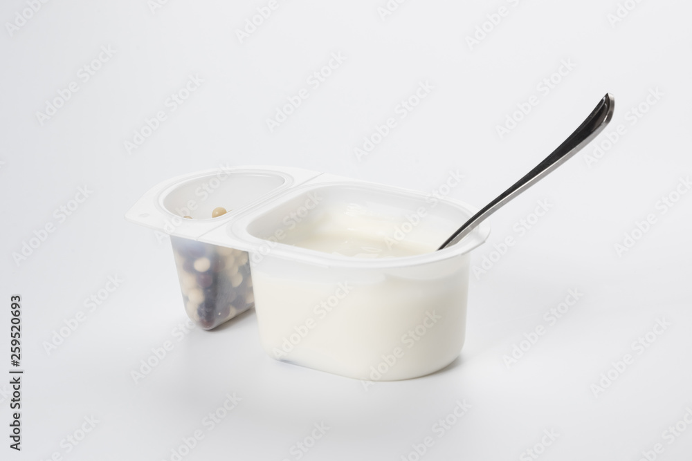 Yogurt with chocolate balls. Double plastic cup with white yogurt and a metal spoon. Yogurt with chocolate balls. Double plastic cup with white yogurt and a metal spoon.