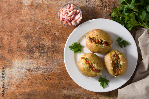 Stuffed potatoes with bacon and cheese on plate on rusty background. Top view