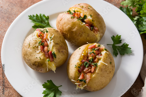 Stuffed potatoes with bacon and cheese on plate on rusty background
