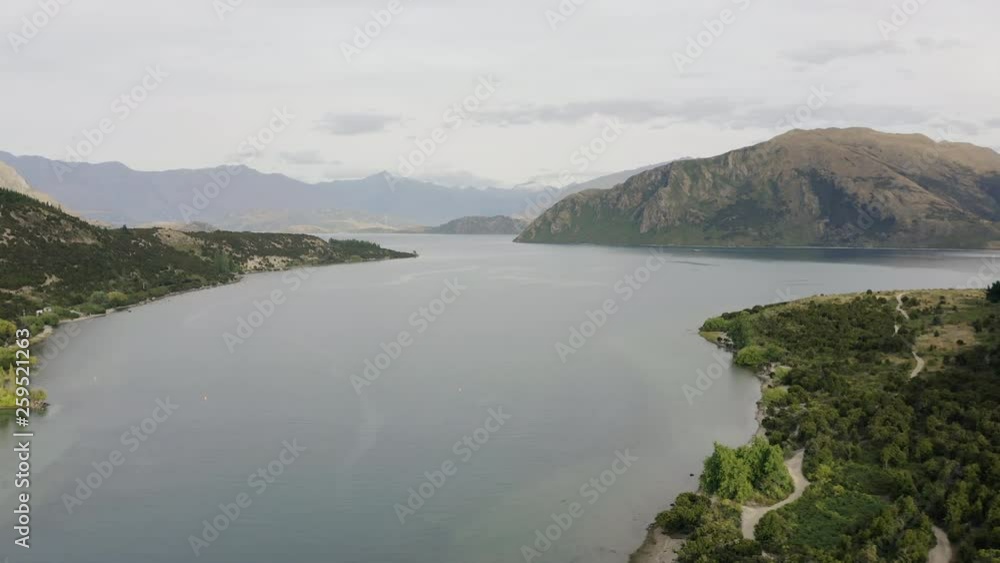 Aerial tracking down lake Wanaka on a still cloudy morning in central Otago as the mountains sit in the sun, Aerial tracking down lake Wanaka on a still cloudy morning in central Otago as the mountains sit in the sun,