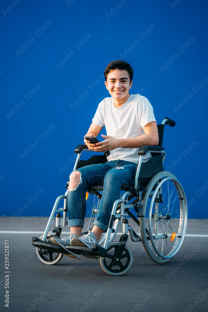 Obraz premium Portrait of young man on wheelchair using mobile phone