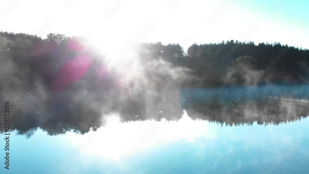 Sunrise over forest in front of foggy lake - panning shot Sunrise over forest in front of foggy lake - panning shot