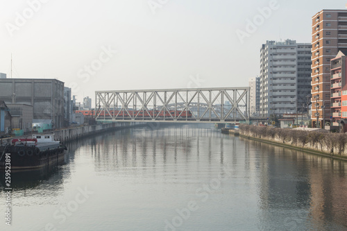 Cityscape with river  bridges  train and buildings in Osaka in spring clear day