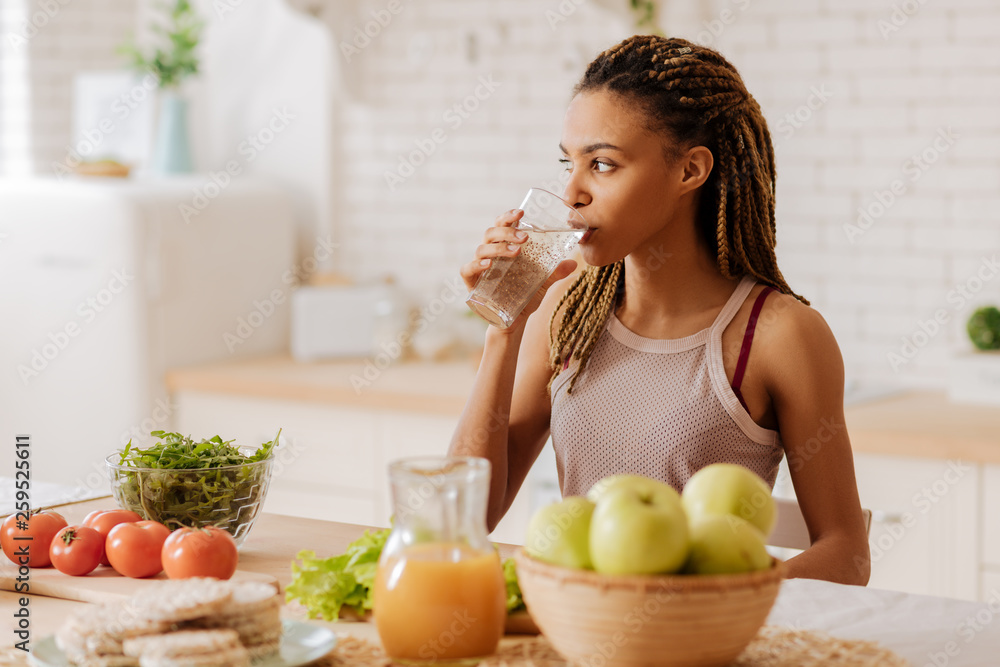 Slim and fit woman drinking water before having breakfast - obrazy, fototapety, plakaty 