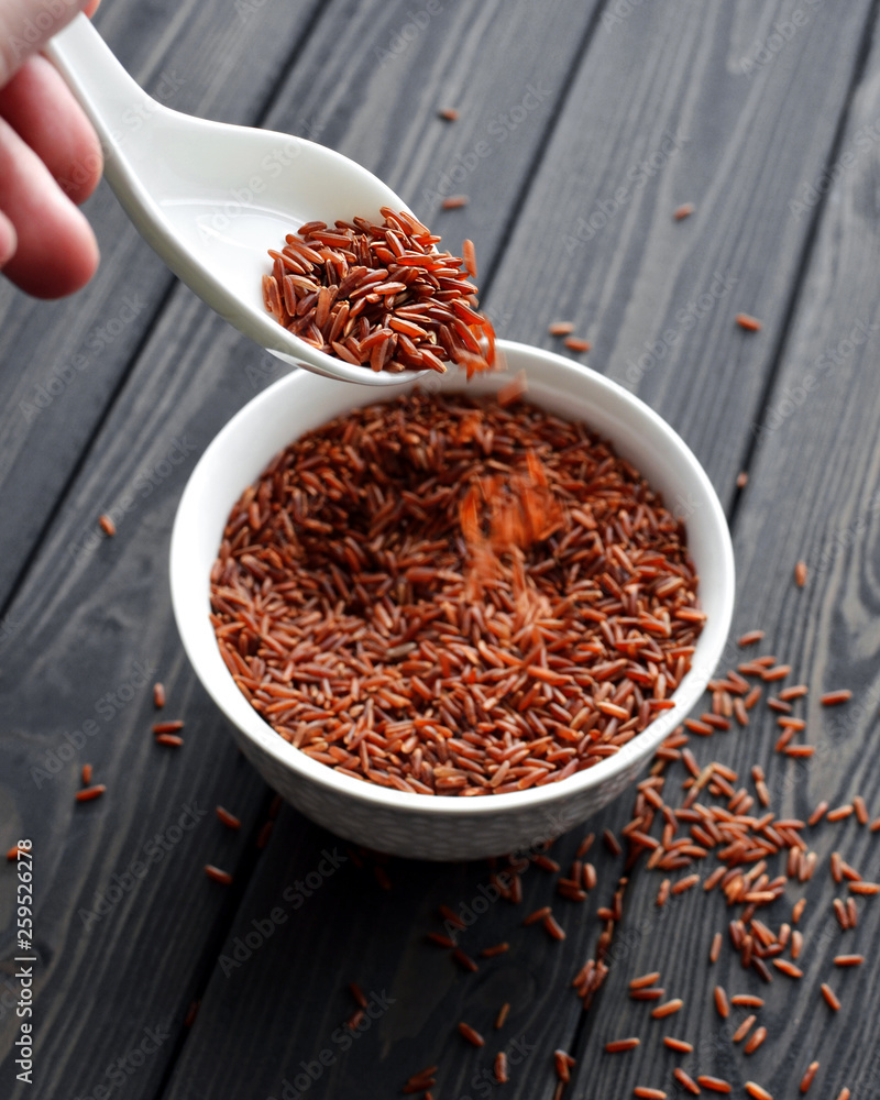 hand holdind a spoon with red rice pouring hand holdind a spoon with red rice pouring