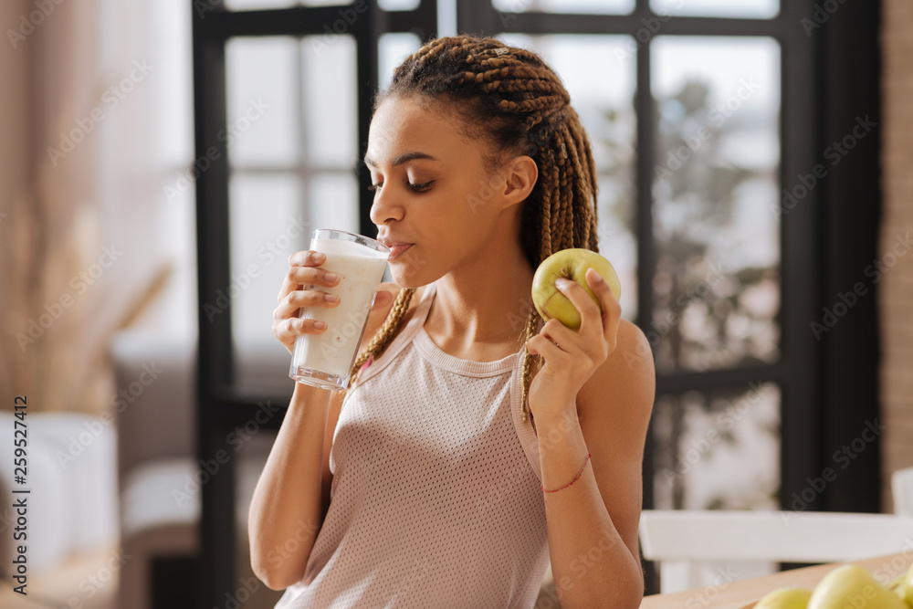 Appealing fit woman wearing sport top drinking glass of milk Appealing fit woman wearing sport top drinking glass of milk