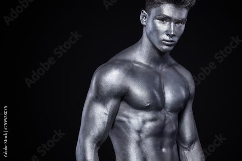 Brutal strong muscular bodybuilder athletic man pumping up muscles on black background. Workout bodybuilding concept. Copy space for sport nutrition ads.