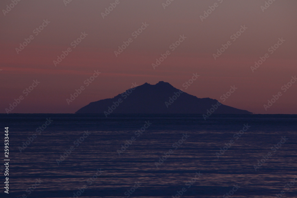 Tramonto invernale visto dalla spiaggia di Marina di Campo sull'isola di Montecristo. Isola d'Elba, Toscana, Italia