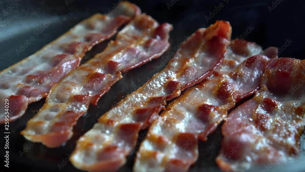 Crispy bacon, rich in fat and colour, sizzling and smoking in a hot pan. Crispy bacon, rich in fat and colour, sizzling and smoking in a hot pan.