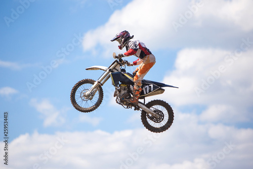 Fototapeta Naklejka Na Ścianę i Meble -  Racer jumping against the blue sky on a motocross championship