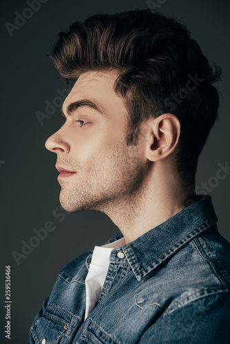side view of handsome and brunette man in denim shirt isolated on black