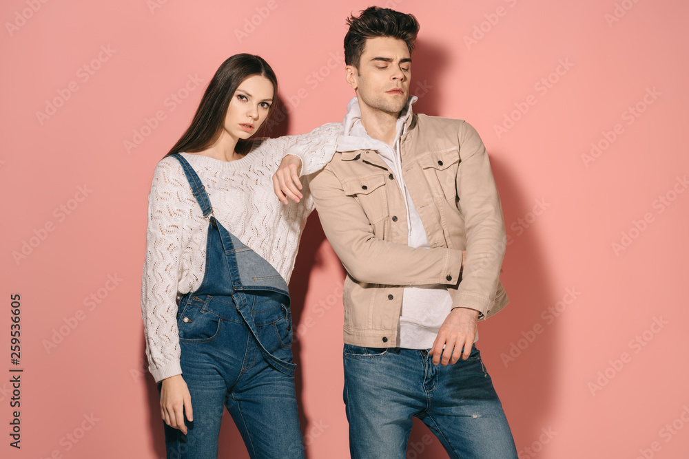 brunette and beautiful girlfriend in denim overalls and handsome boyfriend on pink background