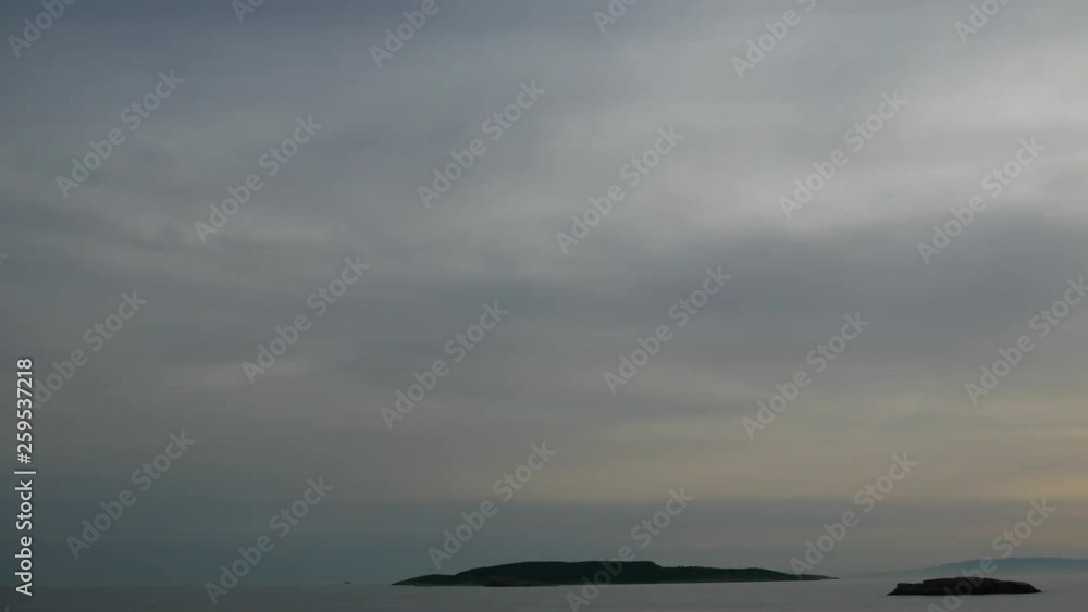 Clouds moving above two small islands in Greece. View from the shore. Sunset in the horizon. Time lapse shot. Clouds moving above two small islands in Greece. View from the shore. Sunset in the horizon. Time lapse shot.