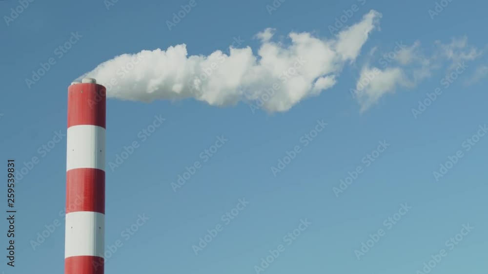 Smoke flows out of chimney at Siekierki power plant in Warsaw, Poland. Clear blue sky in the background. Smoke flows out of chimney at Siekierki power plant in Warsaw, Poland. Clear blue sky in the background.