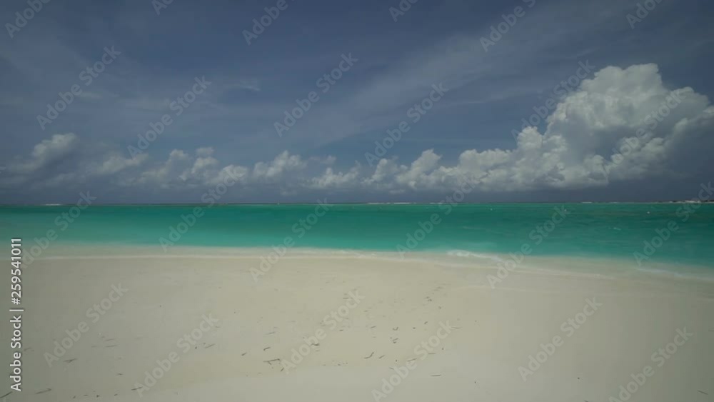 Wide angle shot of waves gently rolling onto a white sandy beach on a clear sunny day Wide angle shot of waves gently rolling onto a white sandy beach on a clear sunny day
