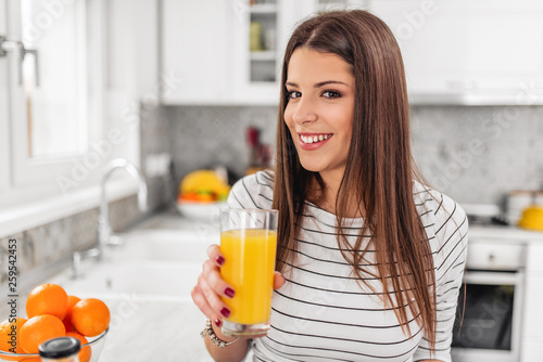 Young teenage girl holding a glass of juice while looking through a window