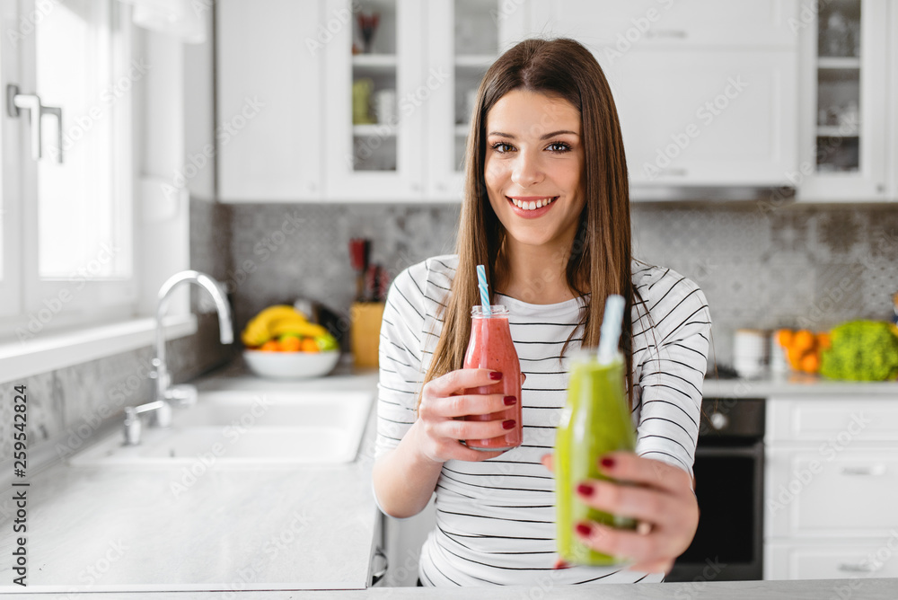 Close up of female hand holding and offering red smoothie in jar. She chose green on. Close up of female hand holding and offering red smoothie in jar. She chose green on.