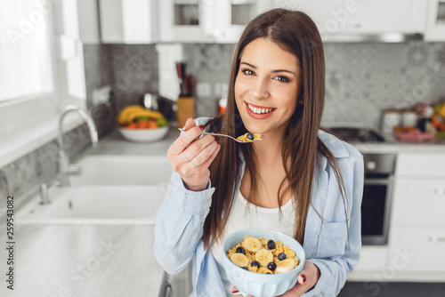 Attractive young woman eating healthy breakfast cereal