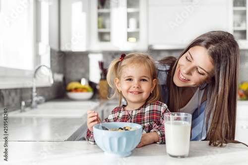Mother and daughter having breakfast with milk at table