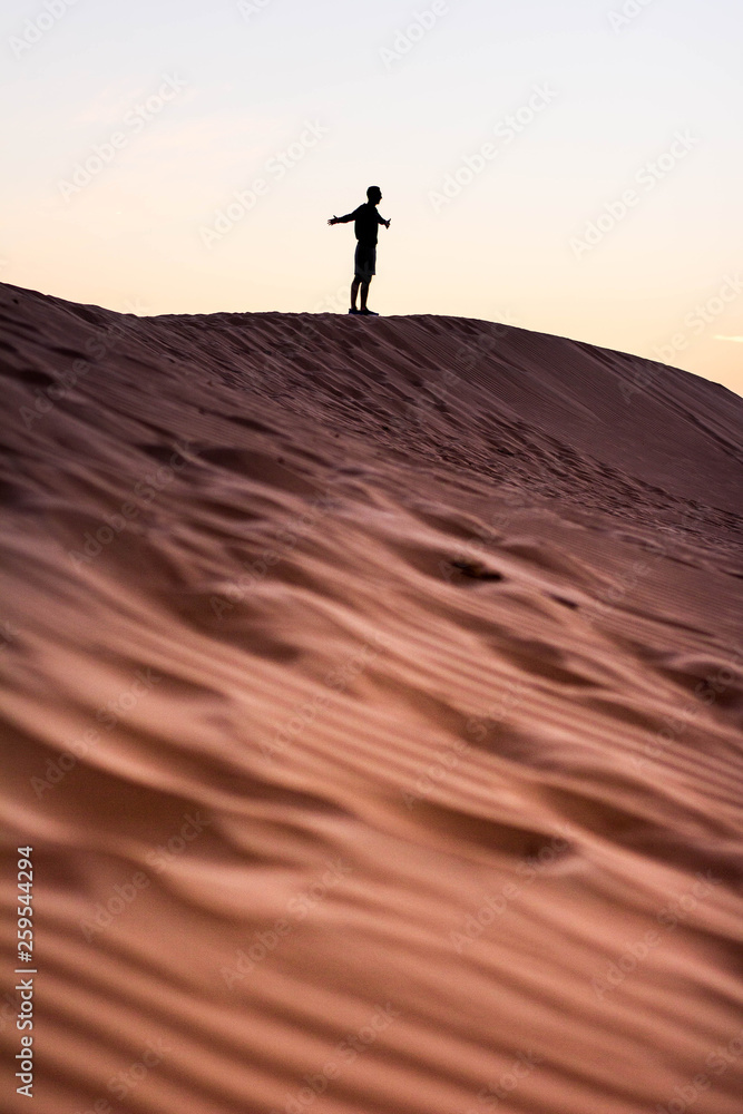 Dark silhouette of a man walking at the desert dunes. Dawn time Dark silhouette of a man walking at the desert dunes. Dawn time