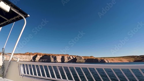 From the deck of a houseboat, the blue waters and sandstone buttes pass by, Lake Powell, Page, ​Arizona photo