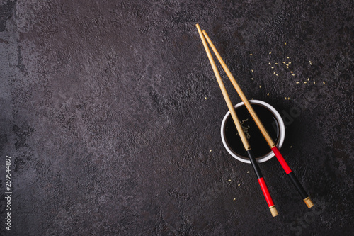 Soy sauce bowl and bamboo chopsticks over black background. Asian cuisine concept