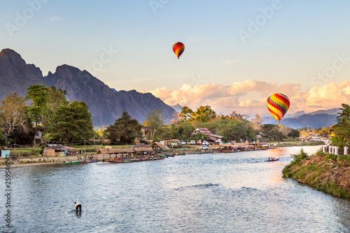 Colorful hot air balloon floating above the river in Vang Vieng city , Laos at sunset 