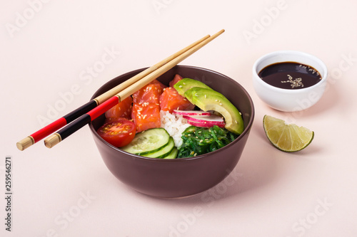 Hawaiian salmon poke with avocado in ceramic bowl on pink background  selective focus