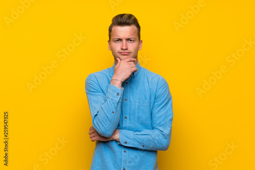Blonde man over isolated yellow wall thinking © luismolinero