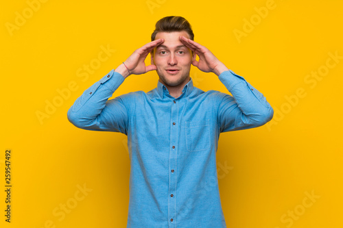 Blonde man over isolated yellow wall with surprise expression