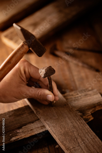 man driving a nail on a wooden cross.
