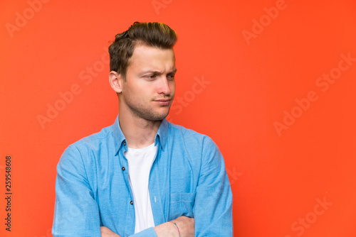 Blonde handsome man over isolated wall standing and thinking an idea