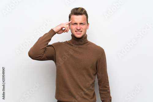 Blonde man over isolated white wall making the gesture of madness putting finger on the head