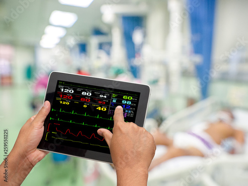 Doctor using tablet to search and check patient medical records in hospital ICU unit.