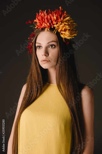 beautiful and brunette woman in elegant dress and wreath looking away isolated on black